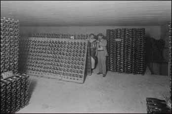 Two men identified as being Edward Emile Bernier (left) and Edmond Mazure working in the champagne cellar at Auldana Vineyards, Magill, S.A. c.1912.